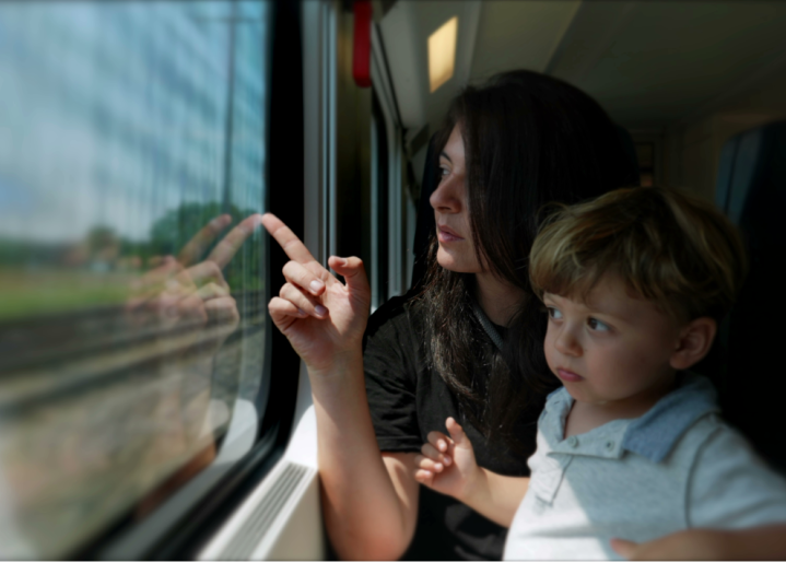 Mutter und Kind reisen gemeinsam mit dem Zug durch die Schweiz und zeigen auf die Landschaft